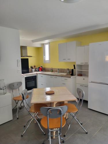 a kitchen with a table and chairs and a white refrigerator at Paisible T2 climatisé avec jardinet in Béziers