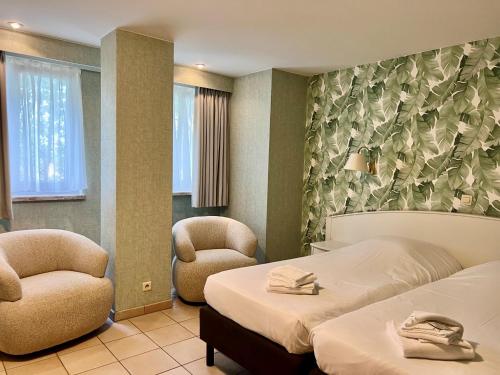 a hotel room with two beds and two chairs at Domein Westhoek in Oostduinkerke