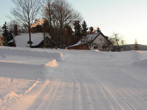 a snow covered road with tracks in the snow at Na Zvonici in Paseky nad Jizerou