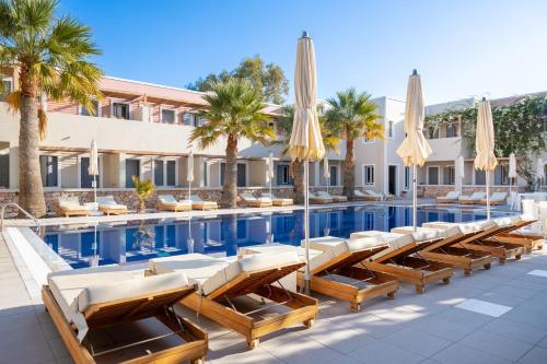 a hotel pool with lounge chairs and umbrellas at Rose Bay Hotel in Kamari