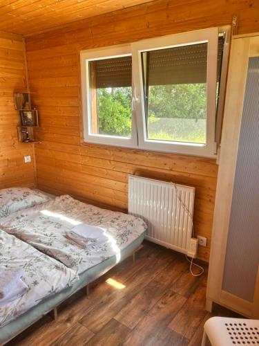a bedroom with two beds in a wooden room with two windows at Luční domek in Protivín