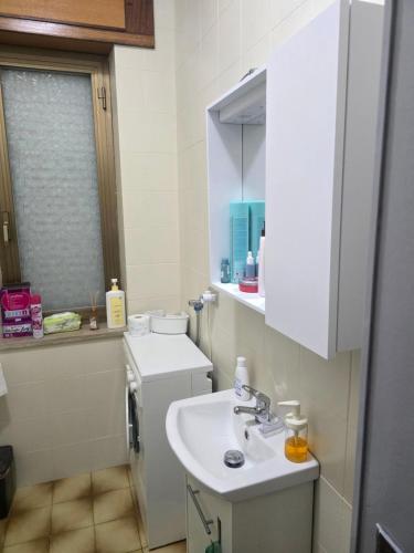 a white bathroom with a sink and a window at Tronca Apartament Kalabria in Marina di Strongoli