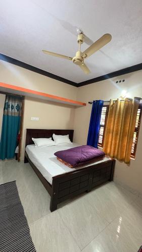 a bedroom with a bed with a ceiling fan at Podanolana residency- Sleep Above the Clouds in Madikeri