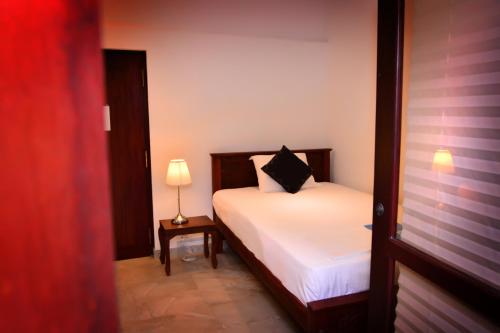 a bedroom with a bed and a lamp on a table at Lucas in Bentota