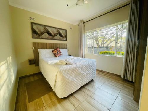 a bedroom with a bed and a large window at Sky Apartments in Harare