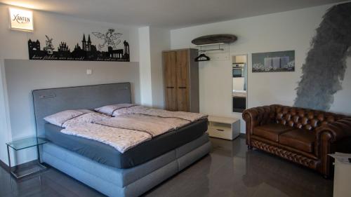 a bedroom with a bed and a leather couch at Ferienwohnung Xantener Südsee in Xanten