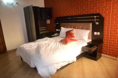 a large bed in a room with a brick wall at ALVI SEVEN Hotel in Douala