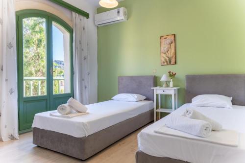 two beds in a room with green walls and a window at Bellevue Apartments in Sitia