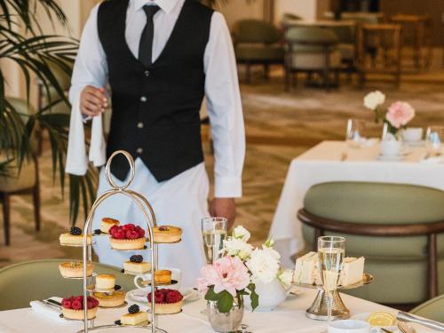 a groom standing in front of a table with desserts at Grecotel Filoxenia Kalamata in Kalamata