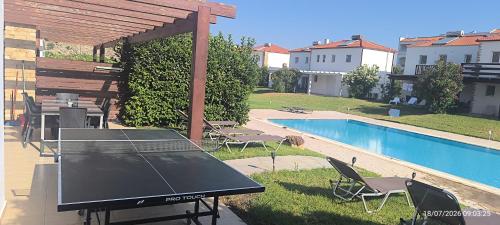 a ping pong table in a backyard with a pool at Villa Kadrina in Kolymbia