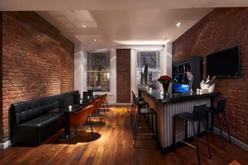 a bar with black leather furniture and a brick wall at Caesar Hotel in London