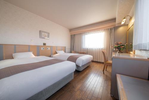 a hotel room with two beds and a table at Takayama City Hotel Four Seasons in Takayama