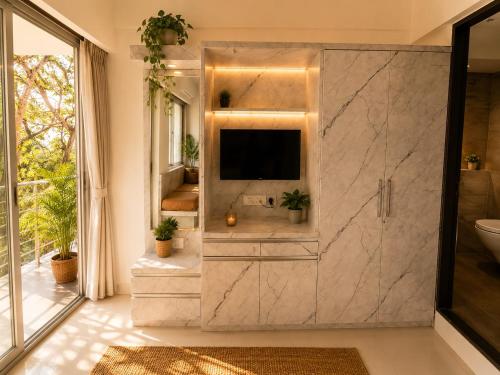 a bathroom with a tv on a marble wall at LuxeBnb - The Olive Maple Room in Pune