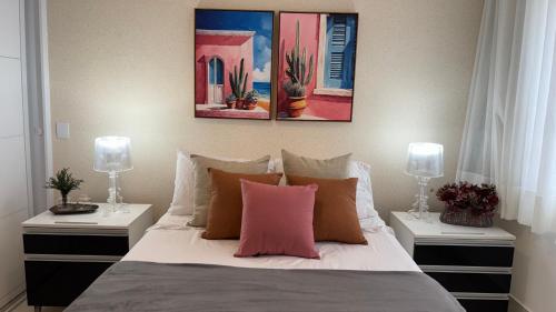 a bedroom with a bed with two lamps and two tables at VR requinte total ar e garagem in Guarapari