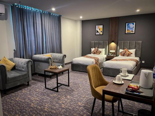 a hotel room with two beds and a table and chairs at Destination Hotel Gilgit in Gilgit
