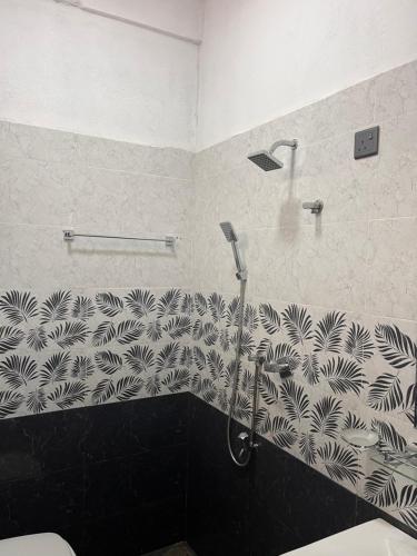 a shower in a bathroom with a black and white wall at RKM Hotel Uppuveli in Trincomalee