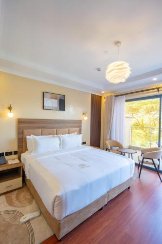 a bedroom with a large white bed and a large window at Sebai Laxury Suit in Nairobi