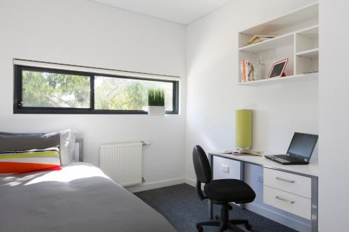 a bedroom with a bed and a desk with a laptop at Western Sydney University Village - Campbelltown in Campbelltown