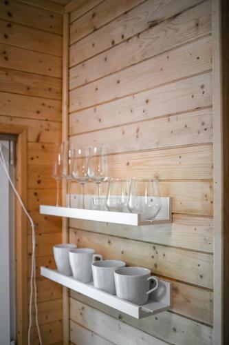 a wooden wall with shelves with cups and glasses at Mama Chata a Mama Spa Beskydy in Bílá