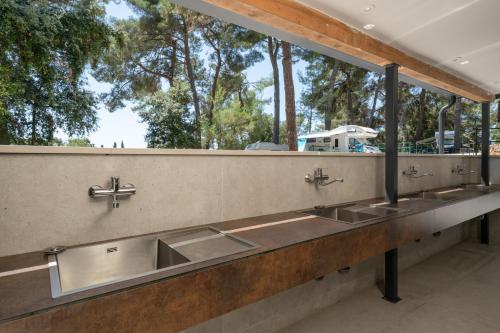 a row of sinks in a public restroom with trees at Porton Nature Hideouts Pitches in Rovinj