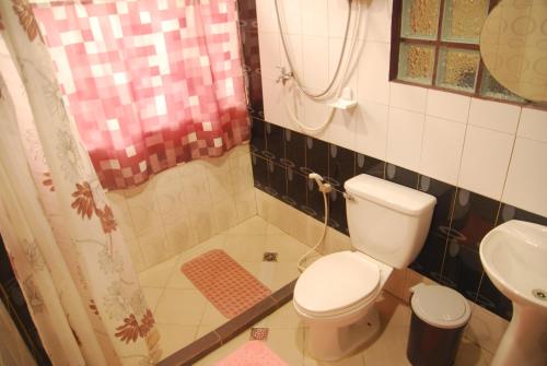 y baño con aseo y ducha. en Centro Mactan Suites en Isla de Mactán