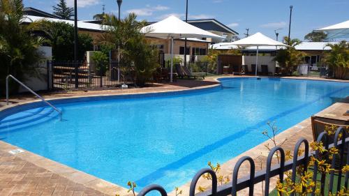 a large blue swimming pool with umbrellas at Nesuto Geraldton in Geraldton