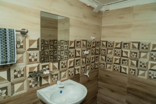 a bathroom with a sink and flowers on the wall at Nilaveli Beach Bungalow in Trincomalee