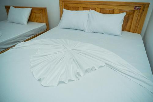 a bed with a white comforter on it at Nilaveli Beach Bungalow in Trincomalee