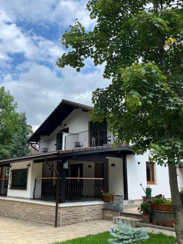 a white house with a balcony and a tree at Casa Carolianne in Bran