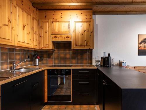 a kitchen with wooden cabinets and a sink at Apartment Wohnung Wettstein by Interhome in Sörenberg