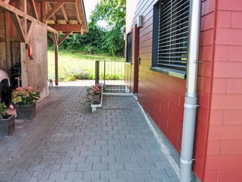 a brick walkway outside of a house with a red wall at Apartment Neuheim by Interhome in Neuheim