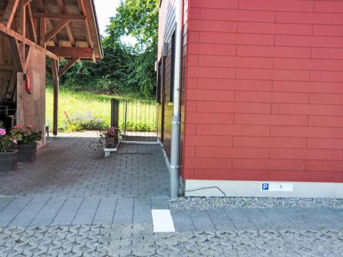 a red wall of a building with a brick sidewalk at Apartment Neuheim by Interhome in Neuheim