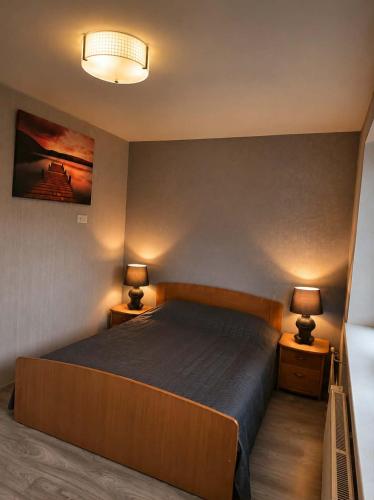 a bedroom with a large bed with two lamps on tables at Apartment in Telšiai