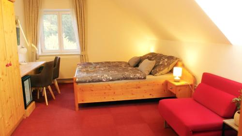 a small room with a bed and a red couch at Bed&Breakfast AmWeinberg in Gamlitz