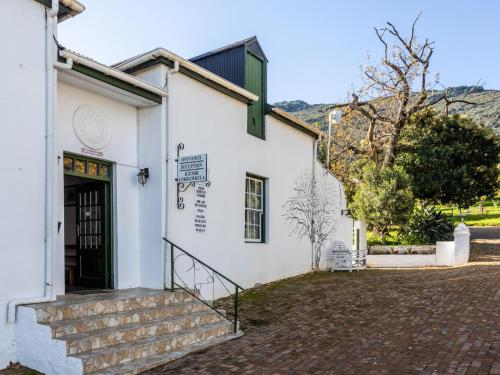 a white building with a staircase leading to the door at Goedgedacht Farm in Malmesbury