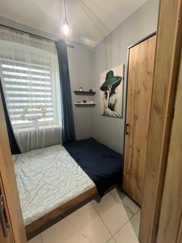 a small bedroom with a bed and a window at Apartament nad rzeką in Głuszyca