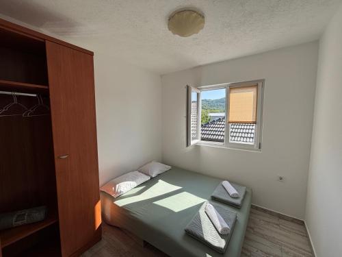 a small bedroom with a bed and a window at Lily Bloom Apartments in Radanovići