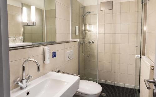 a bathroom with a sink and a toilet and a shower at DORMERO Hotel Essen in Essen