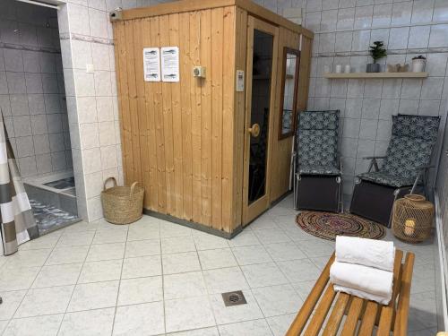 eine Duschkabine aus Holz mit zwei Stühlen und einer Bank in der Unterkunft Park Hotel Gyula in Gyula
