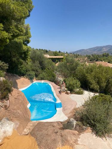 a swimming pool in the middle of a hill with trees at Aldea Roqueta Hotel Rural in Els Ibarsos