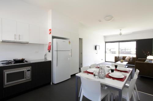 a kitchen with a table and a white refrigerator at Western Sydney University Village - Parramatta in Sydney