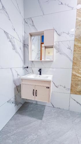 a white bathroom with a sink and a mirror at J&T Holme Villa in Galu