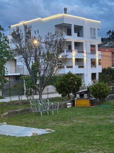 a white building with two chairs in a yard at Apartments Pericic LUX in Sutomore