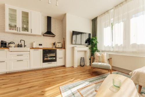 a kitchen with white cabinets and a wooden floor at Townhouse Am Kurpark - Ferienhaus, 2 Schlafzimmer, Arcade, Wallbox, inklusive Wäsche in Braunlage