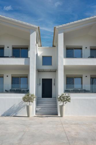 a white building with two plants in front of it at Kleopatra Homes - Napoleontos in Messini