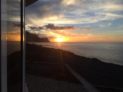 a sunset from a train window with the sun setting over the ocean at Questel BronQ in Chã da Igreja