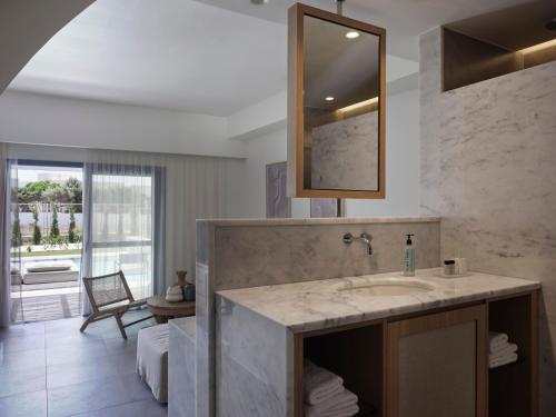 a bathroom with a sink and a mirror at Atlantica Beach Resort Kos in Kardamaina