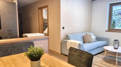 a living room with a blue couch and a table at B living Apartments in Neukirchen am Großvenediger