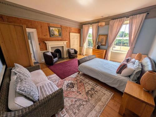 a bedroom with a bed and chairs and a fireplace at The Lawns House in Holt