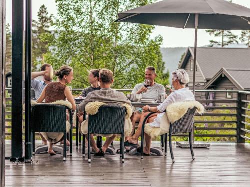 a group of people sitting at a table with an umbrella at Chalet Vrådal by Interhome in Vradal